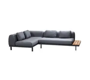L-formet modulsofa i lavagrå med puder og integreret træbord. Sofaen står på ben for støtte.